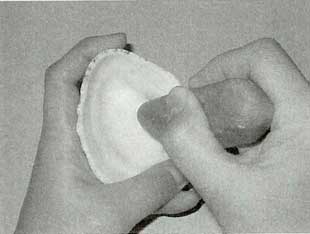 オオツタノハ貝を石を使って貝輪を作る作業をしている写真