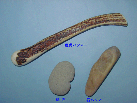 木の棒のような先が丸くなっている鹿角ハンマーと灰色の楕円形の砥石、薄茶色の細長く丸みのある石ハンマーの写真