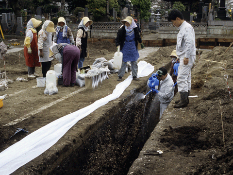 薬剤を塗った貝層断面に水をかけている写真
