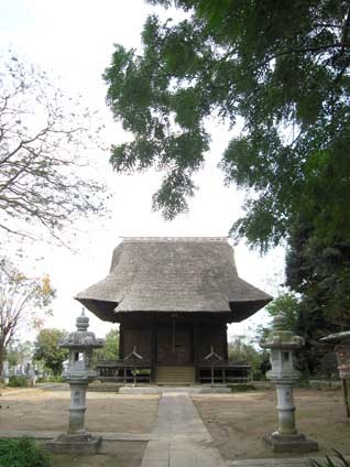 右側に大きな木があり、正面奥に古びた建物、手前両脇に石灯籠がある写真