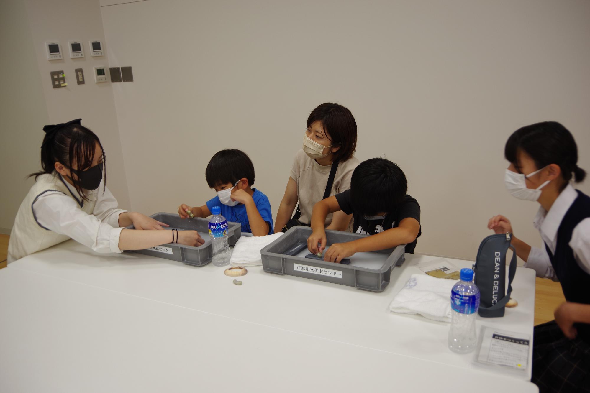 【勾玉づくり】石を削るの疲れたね。砥石（といし）を押さえているからあともう少し削ってごらん。