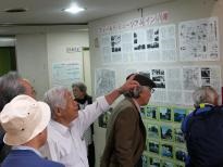 八幡公民館の壁面に掲示されている記事を眺めている高齢男性が映っている写真