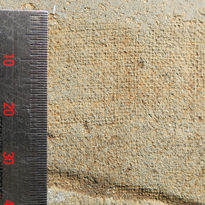 左に物差しがあり、細かい格子模様の跡がついている布の目数を計測している茶色の布の写真
