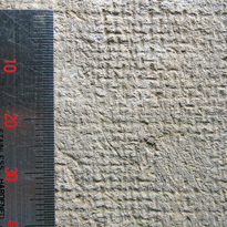 左に物差しがあり、細かい格子模様の跡がついている布の目数を計測している灰色の布の写真
