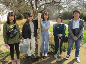 鎌倉街道の道しるべを中心にバケツやショベルを持った5名の高校生が並んでいる写真
