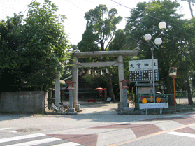 木々に覆われた大宮神社入り口の鳥居を道路から撮影した写真