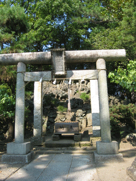 2つの鳥居の奥に祀られている、木々に覆われた浅間神社の塚の写真