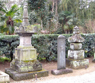 石碑の左隣に四角っぽい石の塔と右隣に丸っぽい石の塔がたっている写真