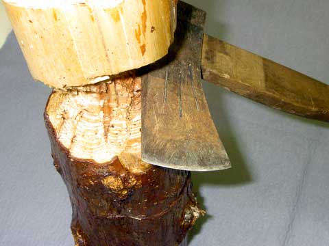 鋭く尖った鉄斧とササクレが少ない伐木の切断面の写真