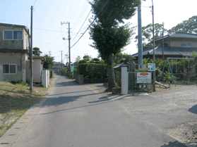 住宅街にあり、ブランコのある公園脇を走る道路の写真