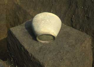 四角い土の台の上に置かれたどんぶりのような形をした白い土器の写真