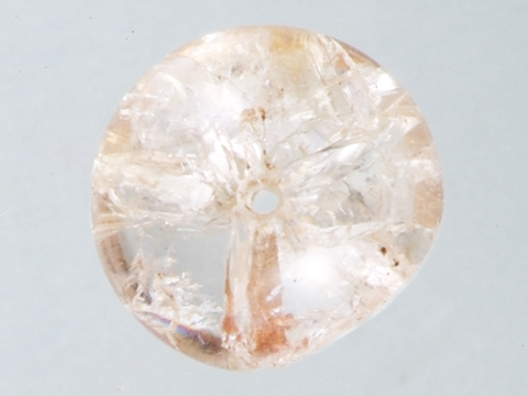 灰色の背景に、白や薄茶色がかったガラス出来た、真ん中に小さく穴の開いた数珠玉の写真