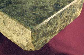 全体に褐色がかった薄い緑色で、やや扁平の長方体で面取りがなされている温石の角部分の拡大写真