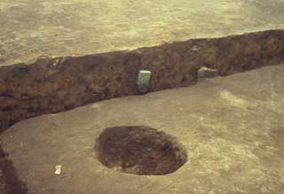 竪穴建物から出土し、まだ土に埋まった状態の温石の写真