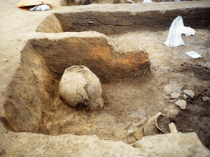 四角く掘った穴の中に壺のような形の石器が置いてある写真