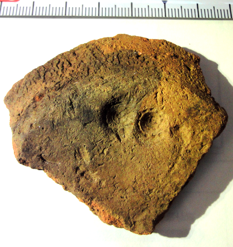 扇型の中心部に二つの丸い圧痕がある黄土色の甕形土器の破片の写真