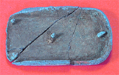 ピンク色の背景に、ターコイズブルーが土で汚れたような色で長方形の小さな三つの突起物があるひび割れた帯の装飾の写真
