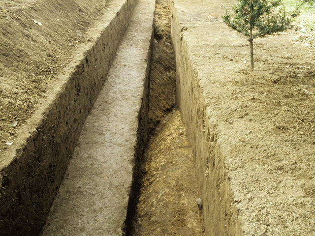 地面が水路のように掘られ、周りがしっかり固められた菊間深道遺跡で発掘された溝の写真