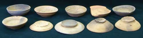黒い背景に、11世紀前葉の黄土色などをした小型杯と小皿が2列に10枚並べられた写真