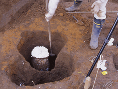 作業員が土の中に石膏を流し込み、周りの土をを掘っている作業の様子の写真