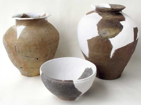 奥に茶色の壺と茶色と白色がまだらになっている壺、手前に灰色と白色の茶碗のようなものが写った写真
