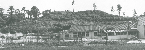平屋の建物の奥に見える山王山古墳の白黒写真