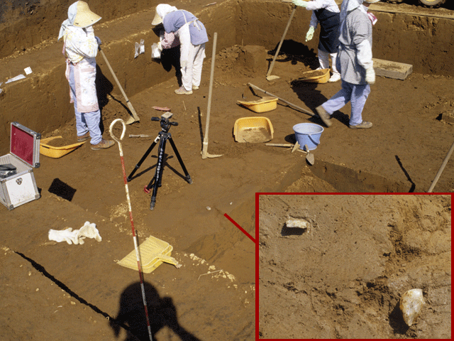 4人の女性が土を掘り、玉髄製の石器が発見された写真。右下に白い小さな2つの石器の拡大写真が載っている。