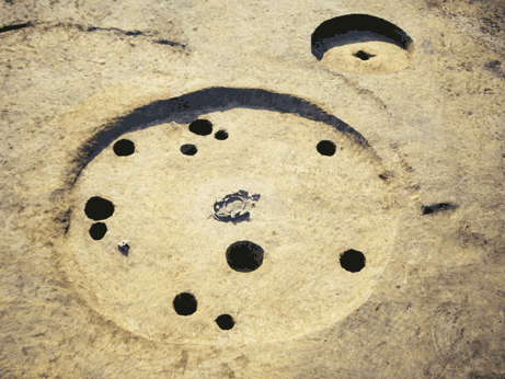 土の地面の円形のくぼみの中に大小の複数の落とし穴が掘られている