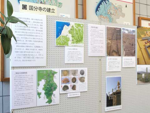 壁に「国分寺の建立」と見出しがあり、その下に地図や写真や説明文のパネルがいくつも掛けられている写真
