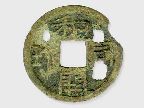右斜め上が欠けている5円玉のような形で中央の穴は四角く、至る所に穴が開いており上から時計回りに「和銅開珎」と漢字で彫られている小銭の写真