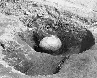 大きな壺のようなものが掘り起こされたモノクロの写真