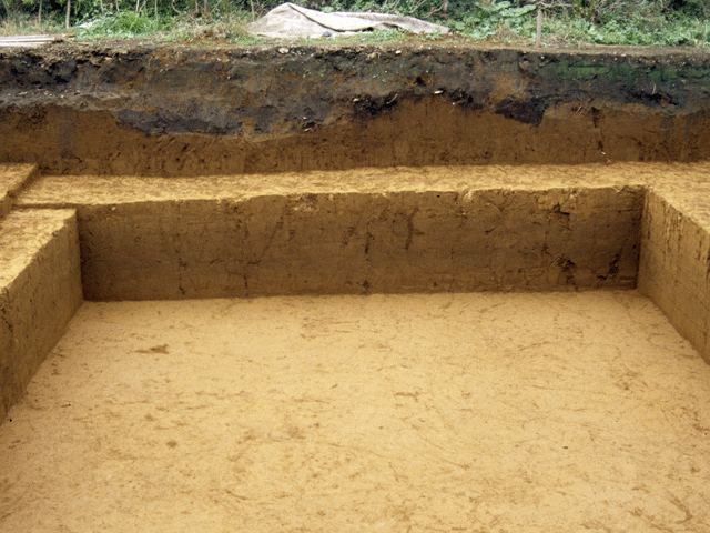 四角い穴が掘られた土の写真。